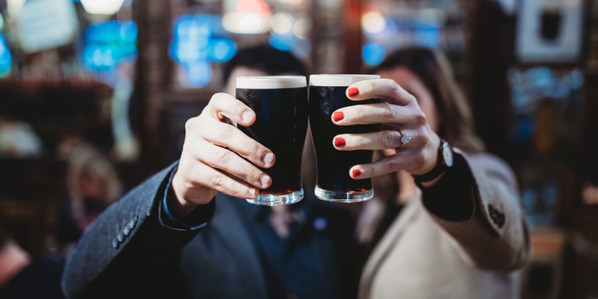 a couple holding glasses full of dark beer