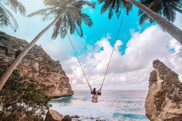 photo of a woman on a treetop swing in bali