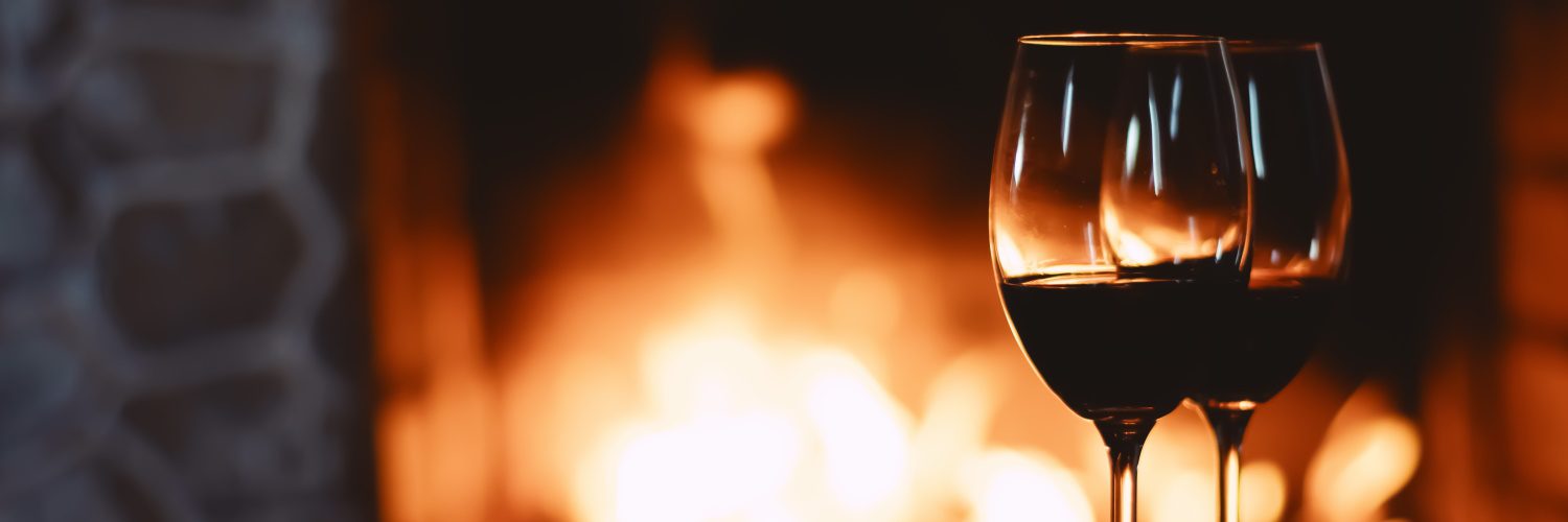 glasses of red wine by fireplace